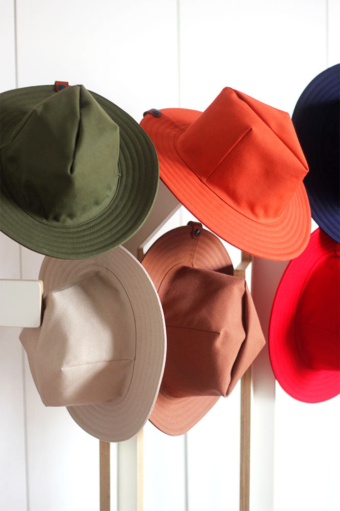 Chapeaux colorés accrochés à un porte manteau. Chapeau design en coton déperlant fabriqué en France. vert kaki, Crème, oisette, orange, rouge, bleu - VPDDLG