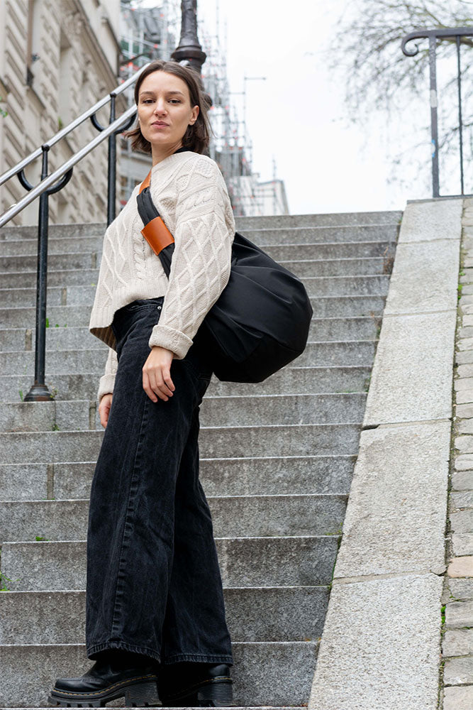 Baluchon noir porté par une femme dans les escaliesr de Montmartre (Paris), sac chic et modulable fabriqué en France, adapté au quotidien - VPDDLG