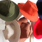 Chapeaux colorés accrochés à un porte manteau. Chapeau design en coton déperlant fabriqué en France. vert kaki, Crème, oisette, orange, rouge, bleu - VPDDLG